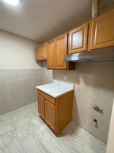 clothes washing area with tile walls and light marble finish flooring