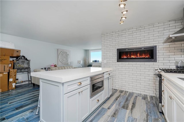 kitchen featuring appliances with stainless steel finishes, open floor plan, wood finished floors, and light countertops