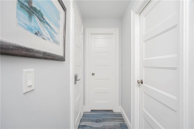 corridor featuring dark wood finished floors and baseboards