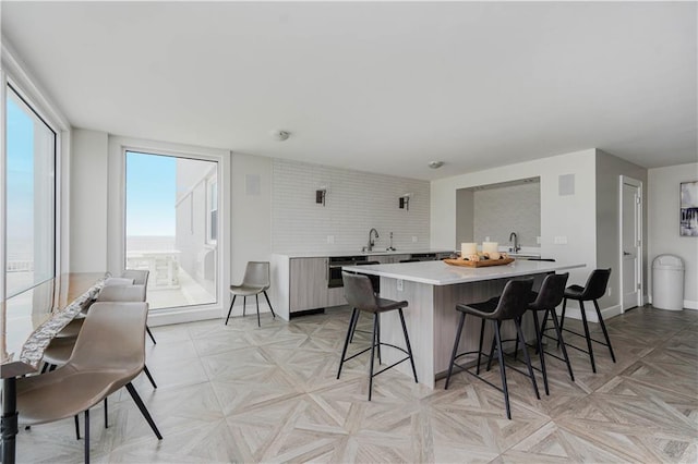 kitchen with light countertops, a kitchen breakfast bar, a sink, a center island, and baseboards