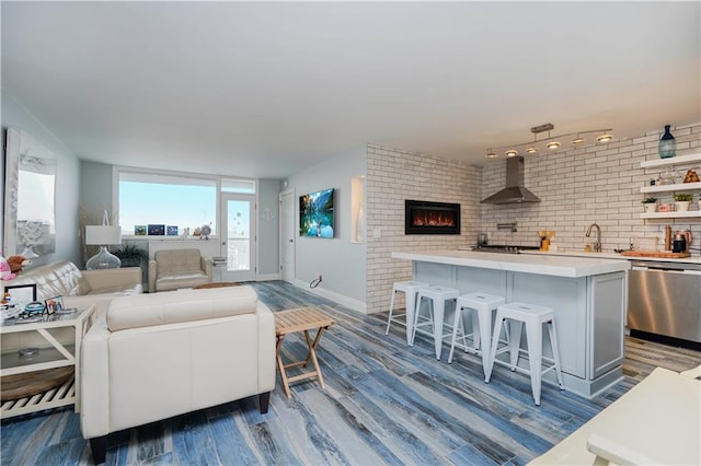living area featuring dark wood-style flooring, baseboards, and a lit fireplace