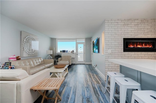 living room featuring wood finished floors, a brick fireplace, and baseboards