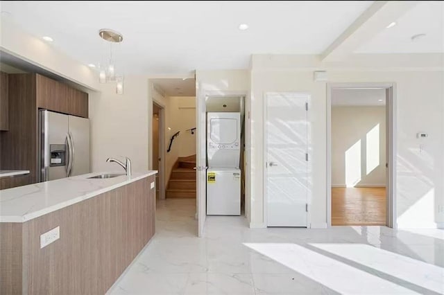 8794 17th Ave Unit 301, Brooklyn, NY 11214 - kitchen with stainless steel refrigerator with ice dispenser, modern cabinets, stacked washer / drying machine, brown cabinetry, and light stone countertops