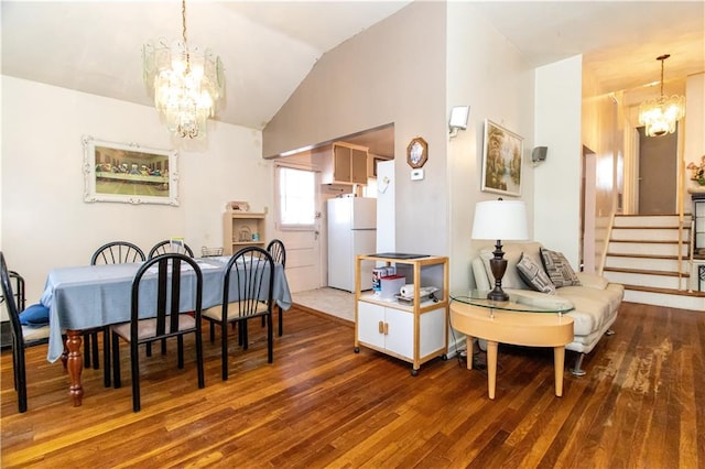 dining room featuring a chandelier, hardwood / wood-style flooring, lofted ceiling, and stairway