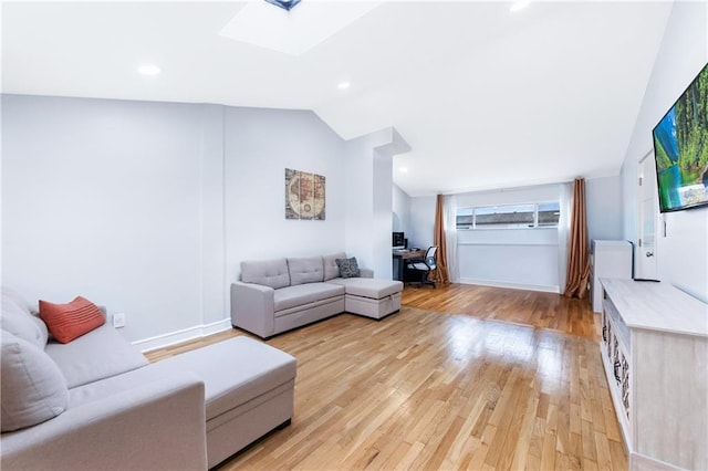 living room with vaulted ceiling, light wood finished floors, a skylight, and baseboards