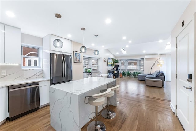 kitchen with freestanding refrigerator, stainless steel dishwasher, a kitchen island, modern cabinets, and light wood-type flooring
