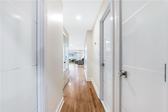hall with light wood-style floors and baseboards