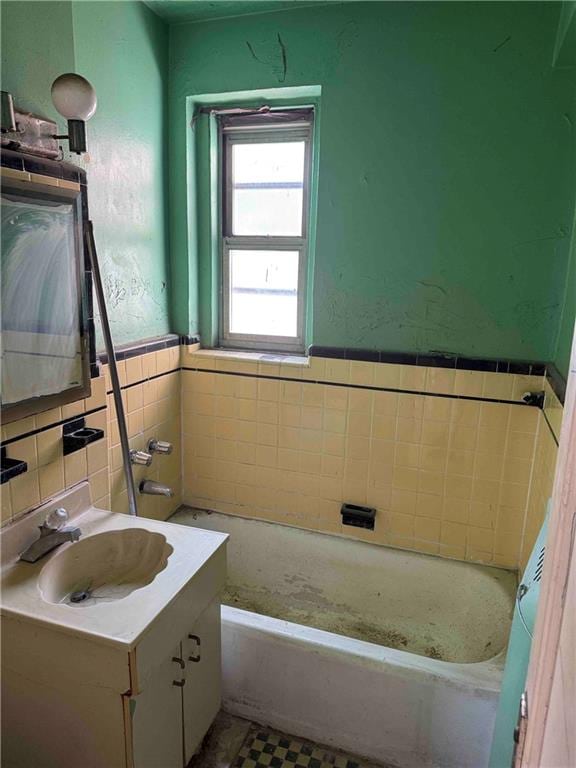 bathroom with tile walls, a wainscoted wall, vanity, and a bathing tub
