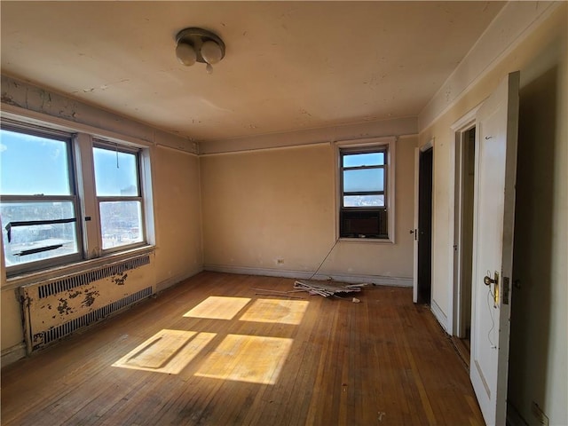 unfurnished room with radiator, baseboards, and hardwood / wood-style floors