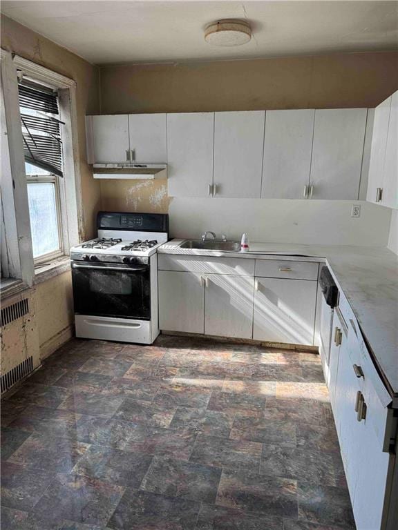kitchen with white cabinetry, light countertops, radiator, under cabinet range hood, and white range with gas cooktop