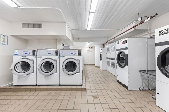 community laundry room featuring washer and dryer, light tile patterned floors, visible vents, and stacked washer / dryer