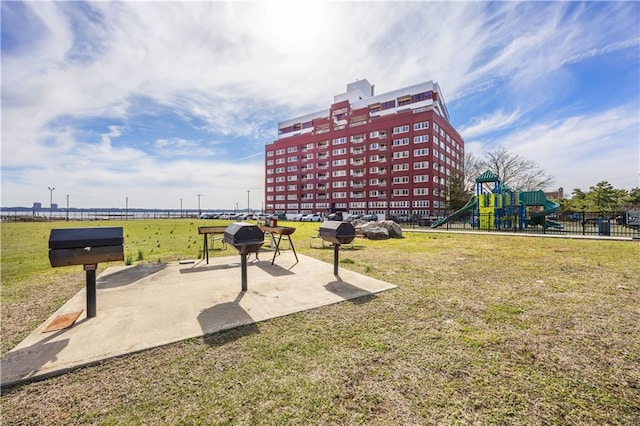 view of property's community featuring a lawn, fence, and playground community