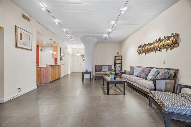living area featuring ornate columns, baseboards, visible vents, and track lighting