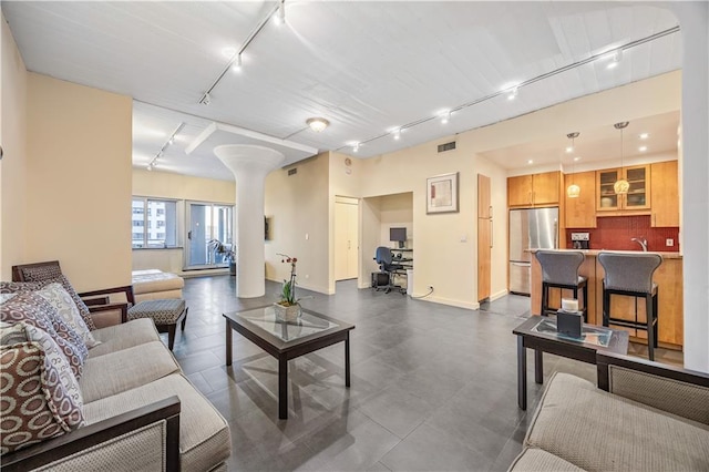 living room featuring visible vents, rail lighting, and ornate columns