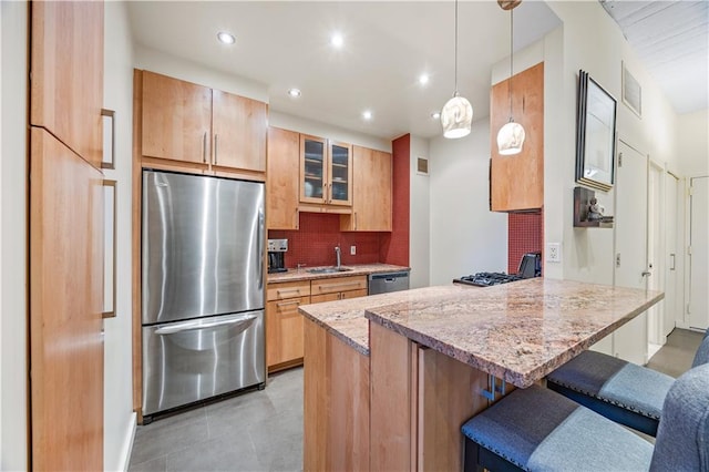 kitchen featuring a breakfast bar, a sink, stainless steel appliances, a peninsula, and decorative backsplash