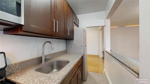 9281 Shore Rd Unit 220, Brooklyn, NY 11209 - kitchen featuring a sink, dark brown cabinets, stainless steel microwave, and light stone countertops