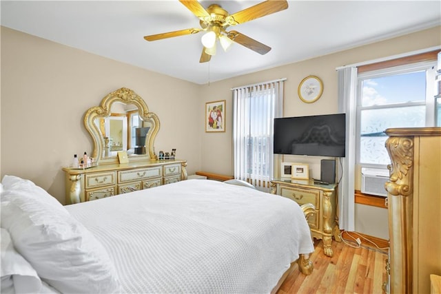 bedroom featuring multiple windows, wood finished floors, cooling unit, and ceiling fan