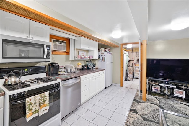 kitchen with stainless steel appliances, light tile patterned floors, white cabinetry, and dark countertops