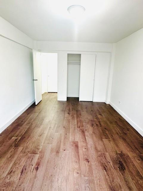 unfurnished bedroom with baseboards, wood finished floors, and a closet