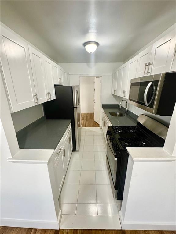 2800 Coyle St Unit 616, Sheepshead Bay, NY 11235 - kitchen featuring appliances with stainless steel finishes, white cabinets, dark countertops, a sink, and light tile patterned flooring
