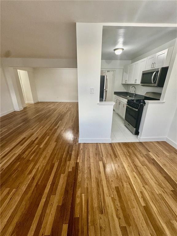 2800 Coyle St Unit 616, Sheepshead Bay, NY 11235 - kitchen with white cabinets, a sink, appliances with stainless steel finishes, open floor plan, and light wood finished floors