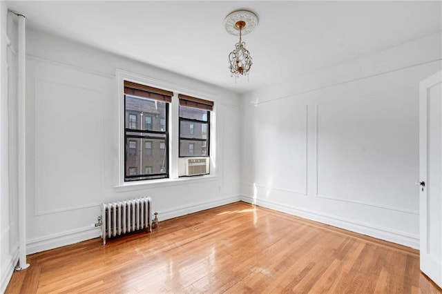 7825 4th Ave Unit E10, Brooklyn, NY 11209 - spare room with radiator heating unit, wood finished floors, cooling unit, and a chandelier