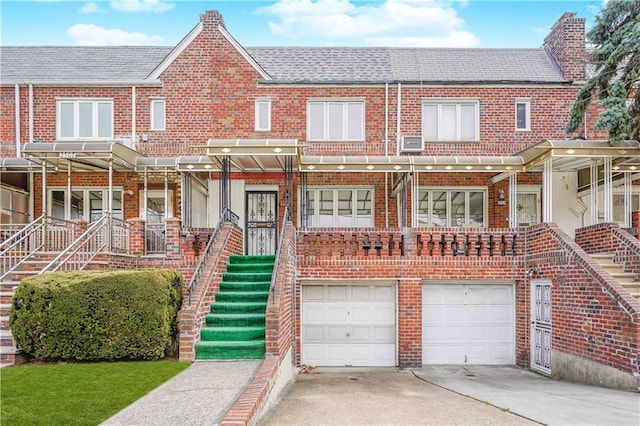 view of property featuring an attached garage, brick siding, concrete driveway, and stairs