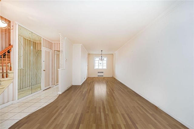 unfurnished room with a chandelier, radiator, crown molding, wood finished floors, and baseboards