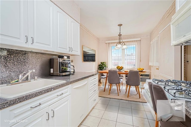 kitchen with white microwave, a sink, light tile patterned floors, decorative backsplash, and white cabinetry