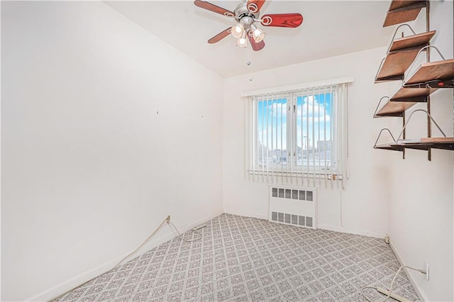 spare room with radiator heating unit, ceiling fan, baseboards, and light colored carpet