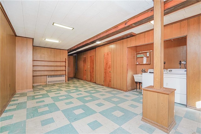 finished basement with washing machine and clothes dryer, tile patterned floors, wood walls, and a sink