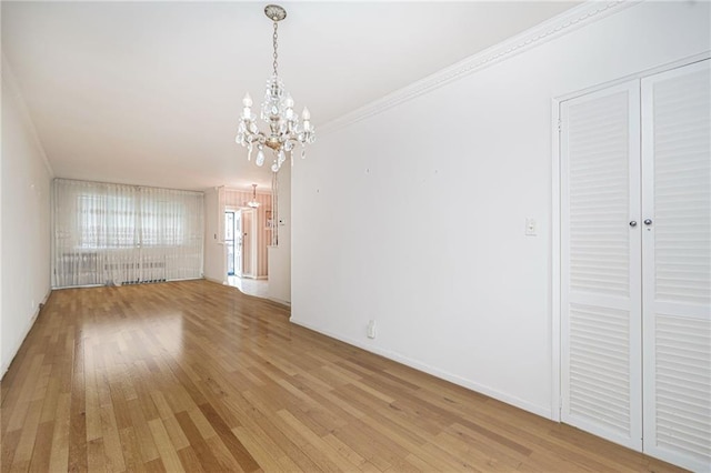 unfurnished dining area with a chandelier, light wood finished floors, and crown molding