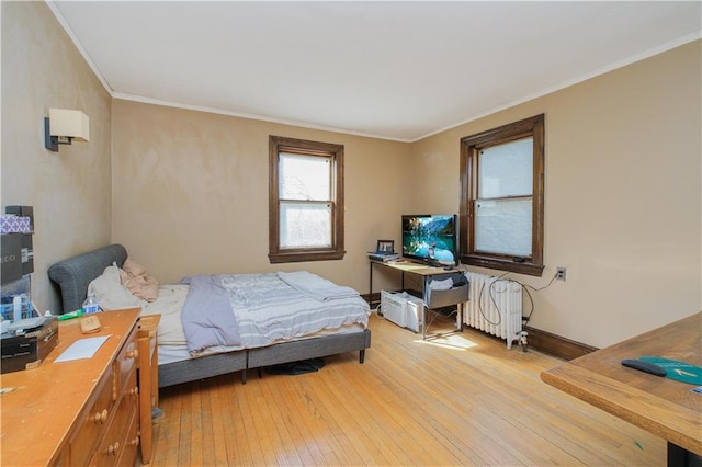 bedroom featuring radiator heating unit, light wood-style flooring, crown molding, and baseboards
