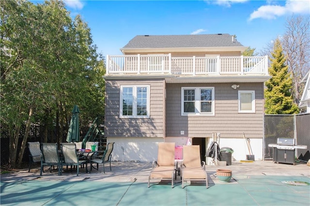 rear view of property with fence, a patio area, a balcony, and a fenced in pool