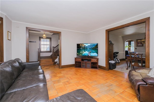 living area featuring arched walkways, baseboards, ornamental molding, and stairway