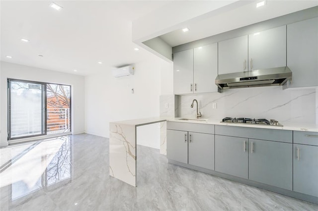 941 57th St Unit 1B, Brooklyn, NY 11219 - kitchen with under cabinet range hood, a sink, a wall unit AC, tasteful backsplash, and stainless steel gas cooktop