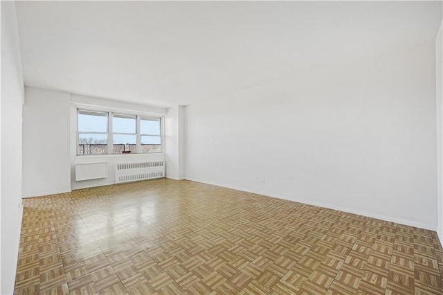 empty room featuring baseboards and radiator heating unit