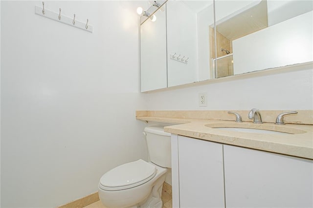 bathroom with toilet, vanity, a shower, and baseboards