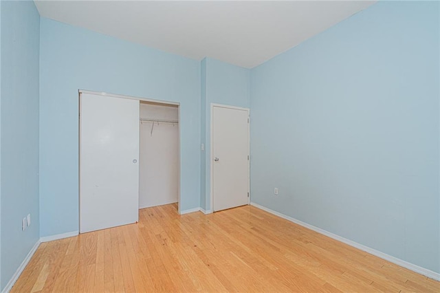 unfurnished bedroom with light wood finished floors, baseboards, and a closet