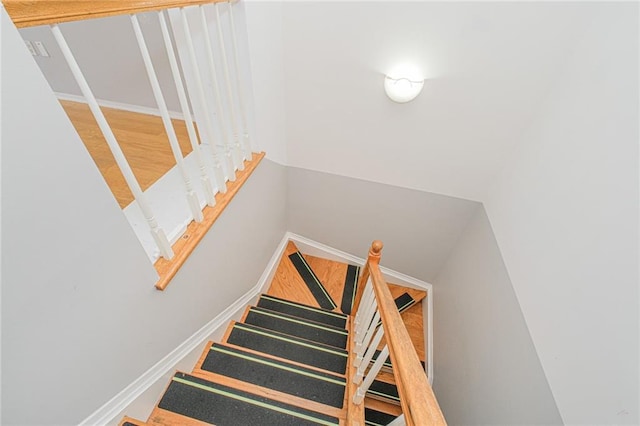 stairway with wood finished floors and baseboards