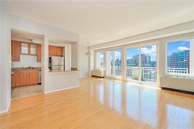 unfurnished living room featuring light wood-style floors, a sink, baseboards, and a city view