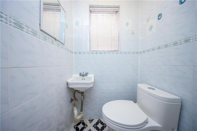 half bath featuring tile walls and toilet
