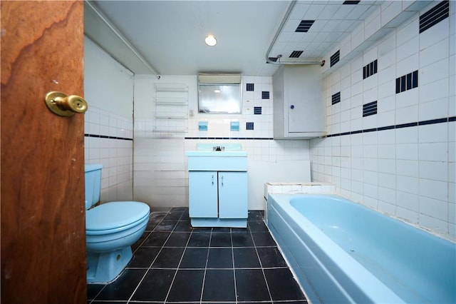 bathroom featuring tile walls, tile patterned flooring, a tub to relax in, toilet, and vanity