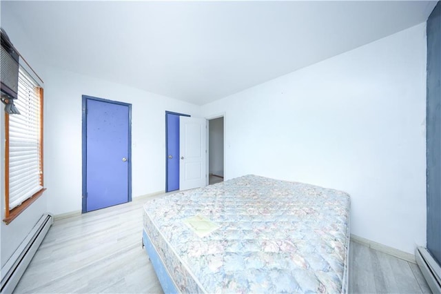bedroom featuring a baseboard radiator, light wood-type flooring, and baseboards