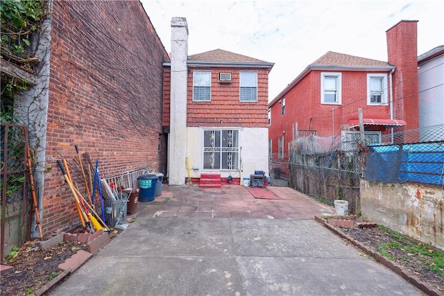 rear view of property with a chimney, a patio, and an AC wall unit