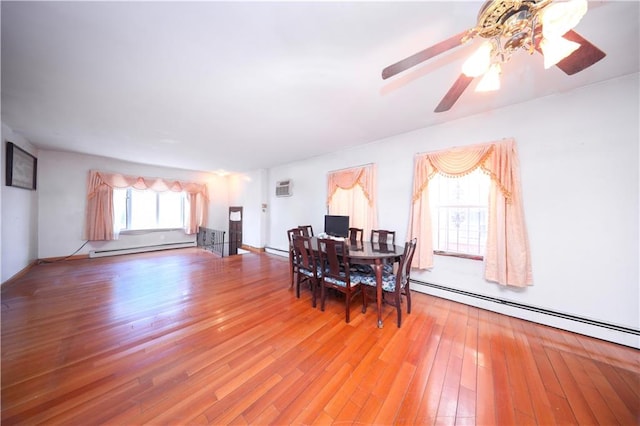 dining area featuring a baseboard heating unit, hardwood / wood-style floors, baseboard heating, a ceiling fan, and a wall mounted AC