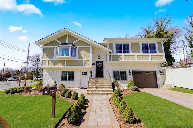 bi-level home featuring fence, an attached garage, brick siding, a front yard, and concrete driveway