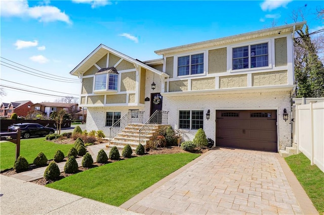 bi-level home featuring brick siding, an attached garage, fence, and a front lawn