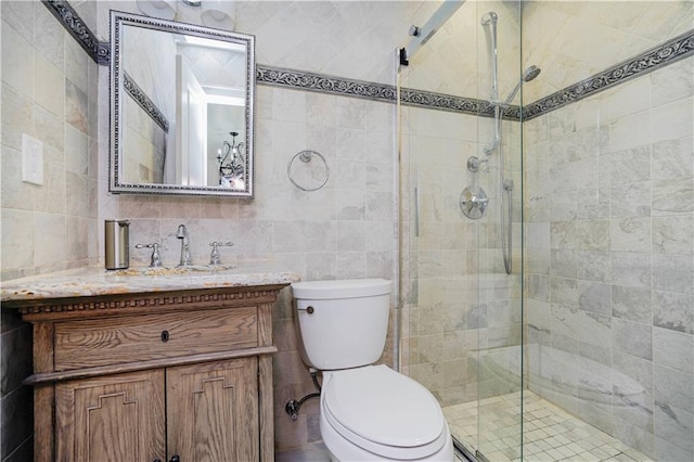 bathroom featuring vanity, a stall shower, toilet, and tile walls