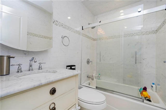 bathroom featuring vanity, toilet, tile walls, tasteful backsplash, and combined bath / shower with glass door